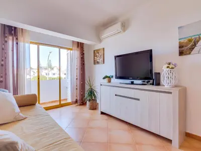 a living room with a tv on a cabinet at AL - Apartamento Quinta do Romão in Quarteira