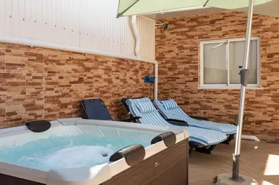 a hot tub with two chairs and an umbrella at Zurrinha holidays whit jacuzzi in Quarteira