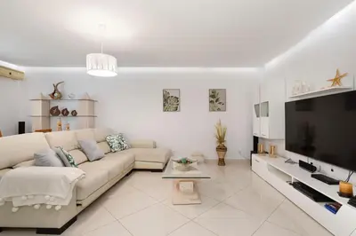 a white living room with a couch and a tv at Zurrinha holidays whit jacuzzi in Quarteira