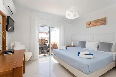 a bedroom with a bed and a desk and a balcony at Zurrinha holidays whit jacuzzi in Quarteira