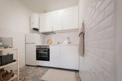 a kitchen with white cabinets and a tile floor at Sunny Days beach apartment in Quarteira