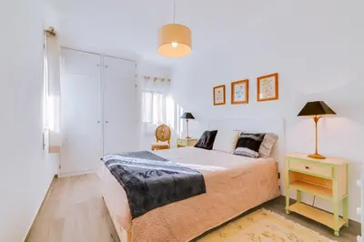 a bedroom with a bed and a table with a lamp at Apartamento Estrela do Mar in Quarteira