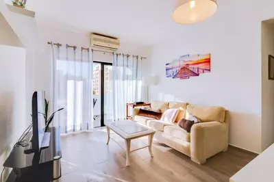 a living room with a couch and a tv at Apartamento Estrela do Mar in Quarteira