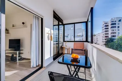 a room with a balcony with a table at Apartamento Estrela do Mar in Quarteira