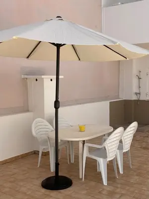 a table with white chairs and a large umbrella at A Minha Praia in Quarteira