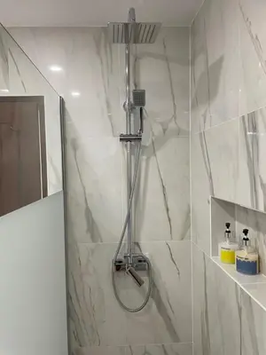 a shower in a bathroom with white marble walls at A Minha Praia in Quarteira