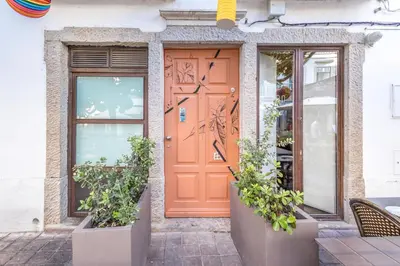 an orange door on a building with potted plants at LODO Suites Ala - Studio mezanino by HD in Faro
