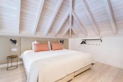 a bedroom with a large white bed with orange pillows at LODO Suites Se - Mezanino room by HD in Faro