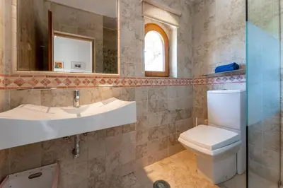 a bathroom with a toilet and a sink and a mirror at The Quinta - 3 Bedroom ensuite Villa, Swimming Pool, Beautiful Gardens, water features and lake in Almancil
