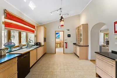 a large kitchen with wooden cabinets and a tile floor at The Quinta - 3 Bedroom ensuite Villa, Swimming Pool, Beautiful Gardens, water features and lake in Almancil