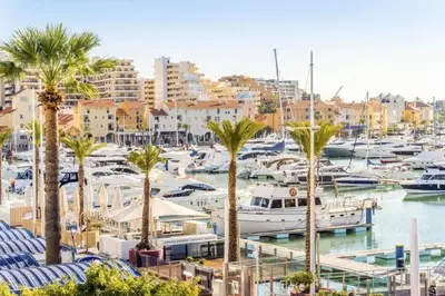 a marina with boats and palm trees and buildings at Villa Brejos in Albufeira