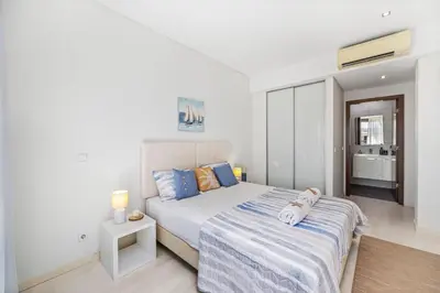 a white bedroom with a bed and a night stand at Seaview Serenity with Pool & Garden in Quarteira