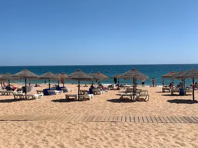 a beach with many chairs and umbrellas and the ocean at T1 Largo Frente - Familiar in Quarteira