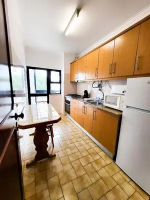 a kitchen with a table and a white refrigerator at T1 Largo Frente - Familiar in Quarteira