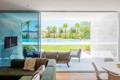 a living room with a couch and a view of a pool at Lakes 24 at Praia da Falesia Vilamoura in Vilamoura