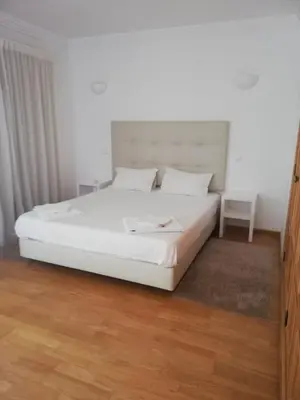a white bed in a bedroom with a wooden floor at Villa V2 V in Olhos de Água