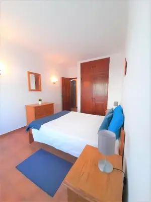 a bedroom with a large bed and a table at T1 MIRA PRAIA a in Quarteira