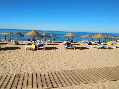 a beach with chairs and umbrellas and the ocean at T1 MIRA PRAIA a in Quarteira