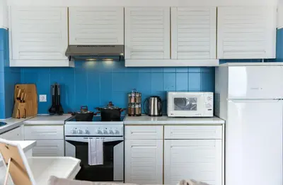 a kitchen with white cabinets and a stove and a microwave at Old Town Apartment Panoramic NearThe Beach in Albufeira