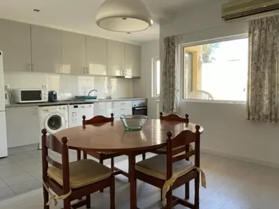 a kitchen with a wooden table and chairs in a kitchen at A Villa in Quarteira