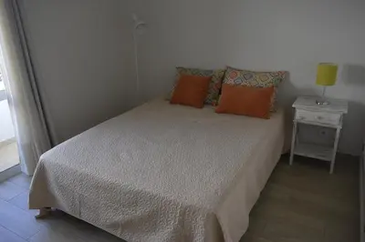 a small bedroom with a bed with orange pillows at Apartamento laranja in Quarteira