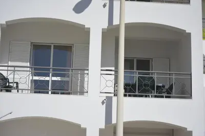 a building with a balcony with a table and chairs at Apartamento laranja in Quarteira
