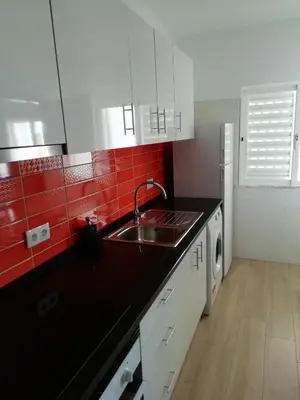 a kitchen with a sink and red tiles on the wall at Apartamento laranja in Quarteira