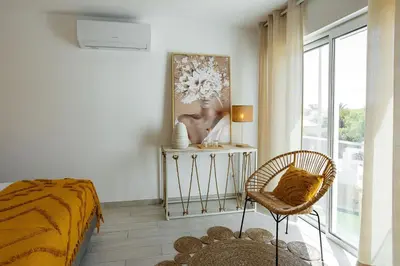 a bedroom with a bed and a chair and a window at Coral Boutique Suites in Albufeira