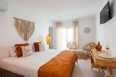 a bedroom with a bed and a table and a television at Coral Boutique Suites in Albufeira