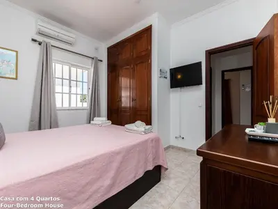 a bedroom with a bed with pink sheets and a dresser at Akisol Albufeira Sun in Albufeira