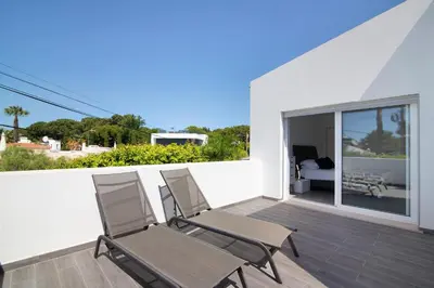 a pair of chairs on a balcony with a bedroom at Pine Lodge in Vilamoura