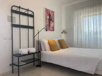a bedroom with a bed and a lamp and a window at Porta 12 in Faro