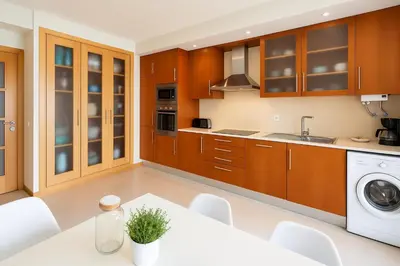 a kitchen with wooden cabinets and a white table at Votre refuge en bord de mer ! in Albufeira