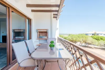 a balcony with white chairs and a table and a plant at Falesia Beach C in Albufeira