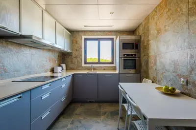 a kitchen with blue cabinets and a table and a window at Falesia Beach C in Albufeira
