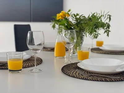 a table with wine glasses and plates and orange juice at Renovated Oasis Ocean View 1BD Wi-Fi Beach 3 min in Albufeira