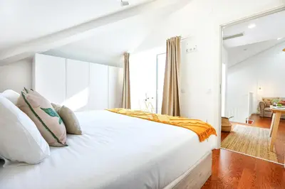 a bedroom with a white bed with white pillows at Ria Formosa Vista Duplex Charm in downtown Faro in Faro