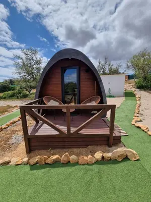 a small dome house with a deck and chairs at Eco Cabin - Villa das Alfarrobas in Algoz