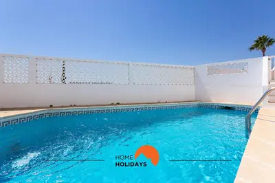 a swimming pool with blue water and a sign that says home holidays at #185 V3 Laranjeiras by Home Holidays in Albufeira