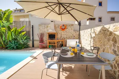 a dining table with an umbrella next to a swimming pool at Private Deluxe 3BD Villa Pool Wi-Fi AC BBQ in Albufeira