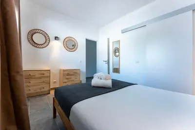 a bedroom with a bed and two mirrors on the wall at Modern 2 BDR Flat W/Balcony and Pool by LovelyStay in Albufeira