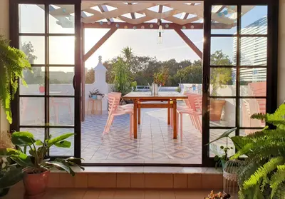 a patio with a wooden table and chairs and large windows at Sunlight House in Faro