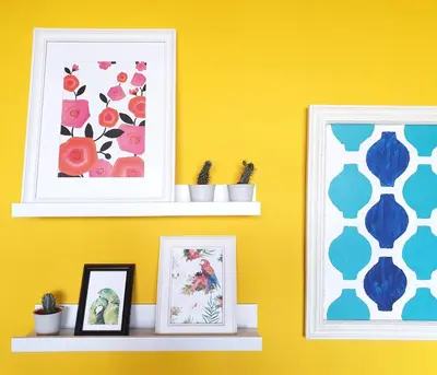 two framed pictures on a yellow wall with two shelves at Sunlight House in Faro