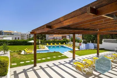 a swimming pool with yellow lounge chairs and a large woodenilion at Palm Tree - Dream Lodging in Albufeira
