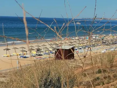 a beach with umbrellas and a crowd of people at EMCA HOME Albufeira in Olhos de Água