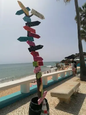 a street sign on the beach next to a bench at EMCA HOME Albufeira in Olhos de Água