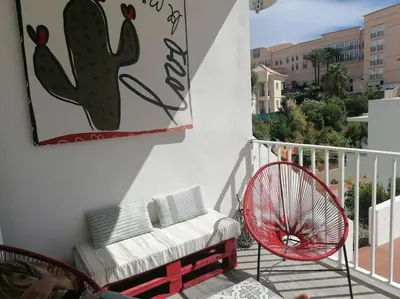 a couch and a chair on a balcony with a cactus painting at EMCA HOME Albufeira in Olhos de Água