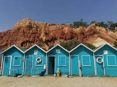 a row of blue beach huts on the beach at EMCA HOME Albufeira in Olhos de Água