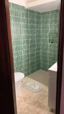 a bathroom with a toilet and a green tiled wall at Casa Calma in Albufeira