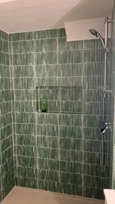 a bathroom with a shower with green tile on the wall at Casa Calma in Albufeira